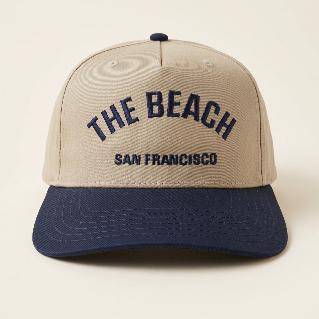 The Beach SF tan and navy hat on an off-white studio background