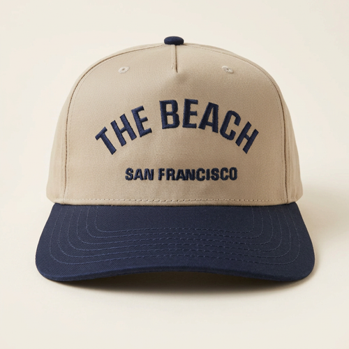 The Beach SF tan and navy hat on an off-white studio background