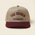The Beach SF tan and maroon hat on an off-white background