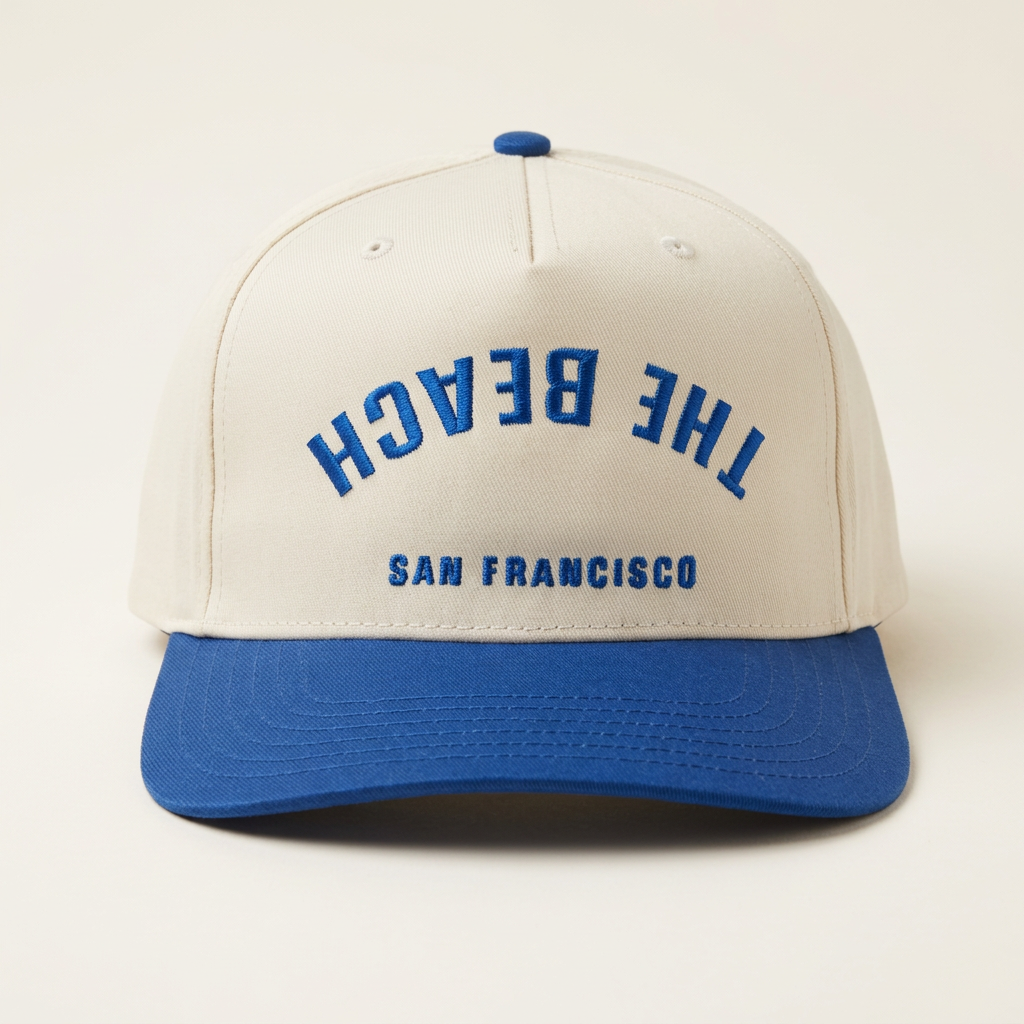 The Beach SF cream and royal blue Flip hat on an off-white background